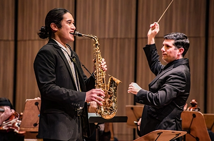 Conductor and saxophone soloist performing with orchestra